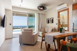 a living room with a dining table and a view of the ocean at Petras Resort in Falasarna