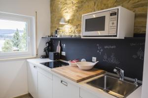 eine Küche mit einer Spüle und einer Mikrowelle in der Unterkunft Kuckucksnest Lenzkirch in Lenzkirch