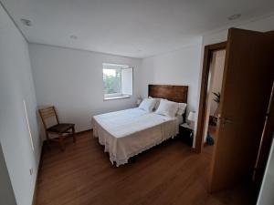 a white bedroom with a bed and a window at A Casa dos Avós - Alojamento Local in Sertã