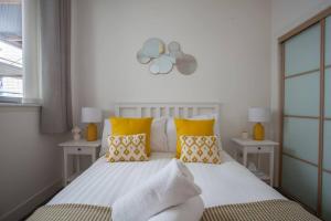 um quarto com uma cama branca e almofadas amarelas em 1 Bedroom Flat in the Heart of Merchant City em Glasgow