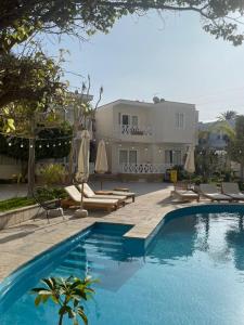 a pool with chairs and umbrellas next to a building at Hotel Emancipador in Paracas
