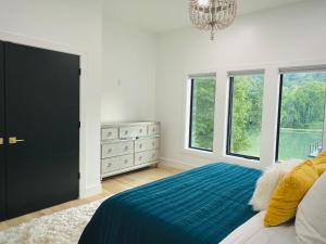 a bedroom with a bed and a chandelier and windows at The Shoal Creek Chateau Lake House in Florence