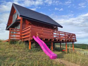 a wooden house with a slide and a playground at Jotwingia - Domki z Widokiem in Stare Juchy