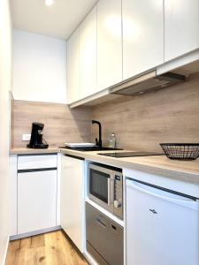 eine Küche mit weißen Schränken und einer Mikrowelle in der Unterkunft Bel appartement en plein centre ville in Limoges