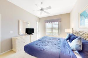 Un dormitorio con una cama azul y un ventilador de techo. en Sail Away, en Bonita Springs