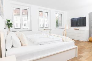 een witte slaapkamer met witte meubels en een flatscreen-tv bij HEIMATEL - City Centre Studio in Ravensburg