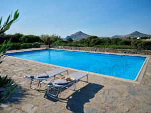 a swimming pool with two lounge chairs next to it at Myrto's House seaview of Naxos in Isterni