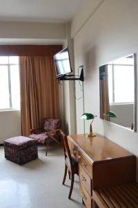 a room with a desk and a tv and a chair at Hotel Calvete in Torreón