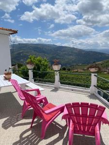 two pink chairs and a table on a balcony at Casa Cecí Douro in Cidadelhe