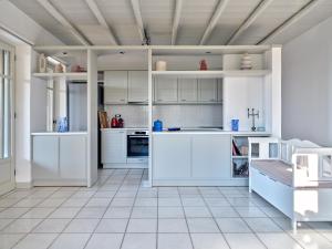 a kitchen with white cabinets and white tile floors at Myrto's House seaview of Naxos in Isterni