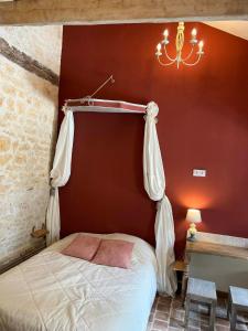um quarto com uma cama com uma parede vermelha e um lustre em Mini gîte royal em Sainte-Gemme-la-Plaine