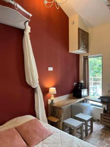 um quarto com paredes vermelhas, uma cama e uma cozinha em Mini gîte royal em Sainte-Gemme-la-Plaine