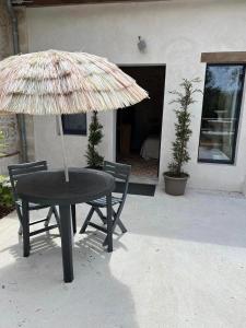 una mesa con sombrilla y 2 sillas en Mini gîte royal, en Sainte-Gemme-la-Plaine