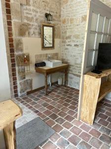 Habitación con baño con lavabo y TV. en Mini gîte royal, en Sainte-Gemme-la-Plaine