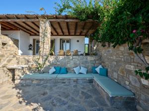a patio with a blue couch under a stone wall at Myrto's House seaview of Naxos in Isterni