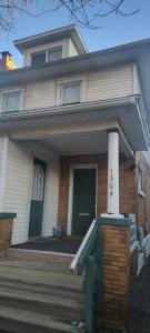 una casa con un porche delantero con una puerta verde en E. Michigan Walk Up Furnished 2 Bedroom APT, en Lansing