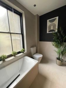 a bathroom with a tub and a toilet and a window at Luxury 2 bed 1 bath in Central London by Graceful Apartments in London