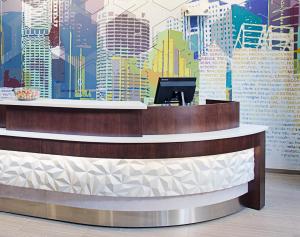 a reception desk with a mural of a city at SpringHill Suites by Marriott Carle Place Garden City in Carle Place