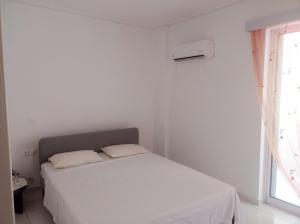 a white bed in a white room with a window at Pireas view in Piraeus