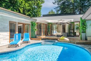 a swimming pool with two blue chairs and a house at Lux White Rock Pool House Beachfront Resort like in Surrey