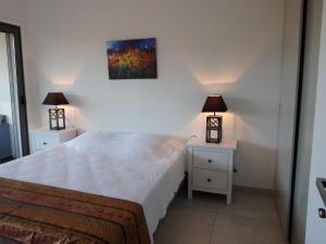 ポルト・ヴェッキオにあるAppartement Cité Du Selのベッドルーム1室(ナイトテーブル2台、ランプ付)