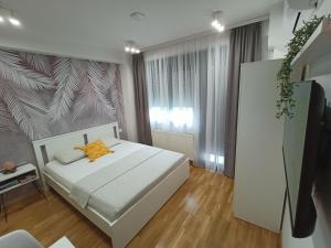 a bedroom with a white bed with a yellow pillow at Apartman Luxor in Jagodina