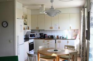 eine Küche mit einem Tisch und Stühlen sowie eine Küche mit weißen Schränken in der Unterkunft Sörgårdens Logi in Härnösand