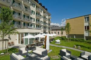 a hotel with tables and umbrellas in a courtyard at Sorell Hotel Tamina in Bad Ragaz