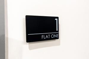 a sign that reads flat one on a white wall at 1BR Derby City Centre Flat 1 - Charnwood Flats in Derby