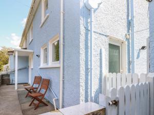 a blue house with a white fence and two chairs at Afan House in Port Talbot