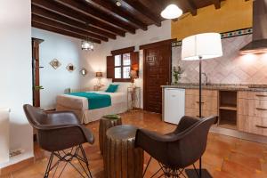Habitación de hotel con 1 cama y 2 sillas en SUITES CASA DE LAS COLUMNAS, en Granada