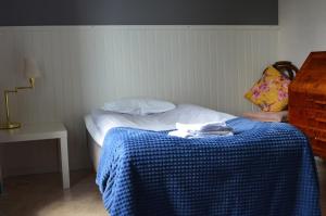 Dormitorio pequeño con cama con manta azul en Sörgårdens Logi, en Härnösand
