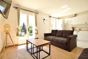 ein Wohnzimmer mit einem Sofa und einem Tisch in der Unterkunft Charmante Maisonnette, aux plateaux fleuris in Saint-Laurent-du-Var
