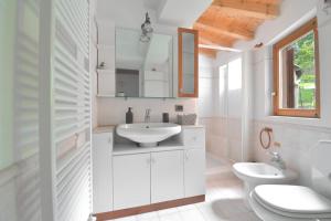 uma casa de banho branca com um lavatório e um WC em Baceno Home em Baceno