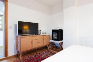 a living room with a tv on a wooden dresser at Zimmer am Weinberg in Deutschlandsberg