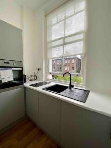 uma cozinha com um lavatório e uma janela em Stylish Studio near Regents Park n6 em Londres
