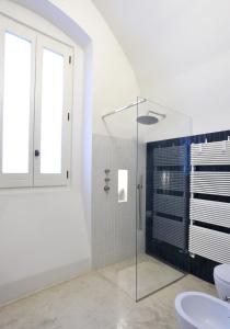 y baño con ducha de cristal y aseo. en Unamura - dimora storica, en Nardò