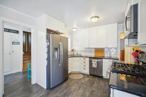 a kitchen with white cabinets and a stainless steel refrigerator at Charming Pet Friendly Coastal Getaway home in Fort Bragg