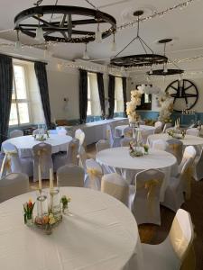 a banquet hall with white tables and white chairs at Saracens Head Hotel by Greene King Inns in Towcester