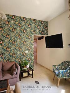 sala de estar con sofá y TV de pantalla plana en Latidos de Triana - ático con vistas a todo Sevilla en Sevilla