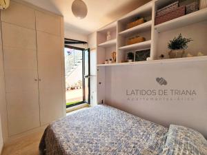 a bedroom with a bed and a large window at Latidos de Triana - ático con vistas a todo Sevilla in Seville
