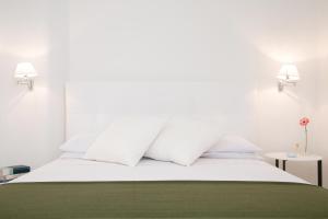 Cama blanca con almohadas blancas y manta verde en Elamar en Gallipoli