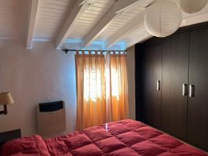 1 dormitorio con cama roja y ventana en Dos Aguas en Tunuyán