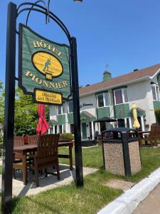 a sign for a hotel in houston with a bench and a trashcan at Hotel Le Pionnier in Tadoussac