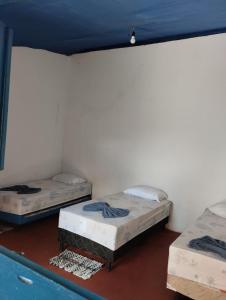 three beds in a room with a wall at Pousada da Dora in Prado