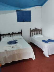 two beds in a room with white walls at Pousada da Dora in Prado