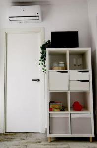 ein weißes Bücherregal mit einem Fernseher und einer Tür in der Unterkunft La Marieta, casita acogedora y centrica in Castilleja de la Cuesta