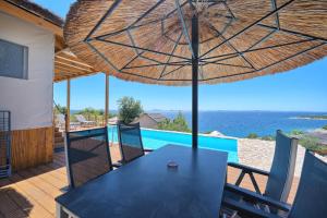 a table and chairs under a umbrella on a patio at Golden Haven Luxe Glamp Resort in Murter