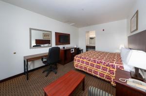 a hotel room with a bedroom with a bed and a desk at America Inn & Suites in Ridgecrest