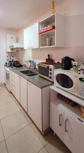 cocina con armarios blancos y microondas en "Valentino hostel" en Ezeiza